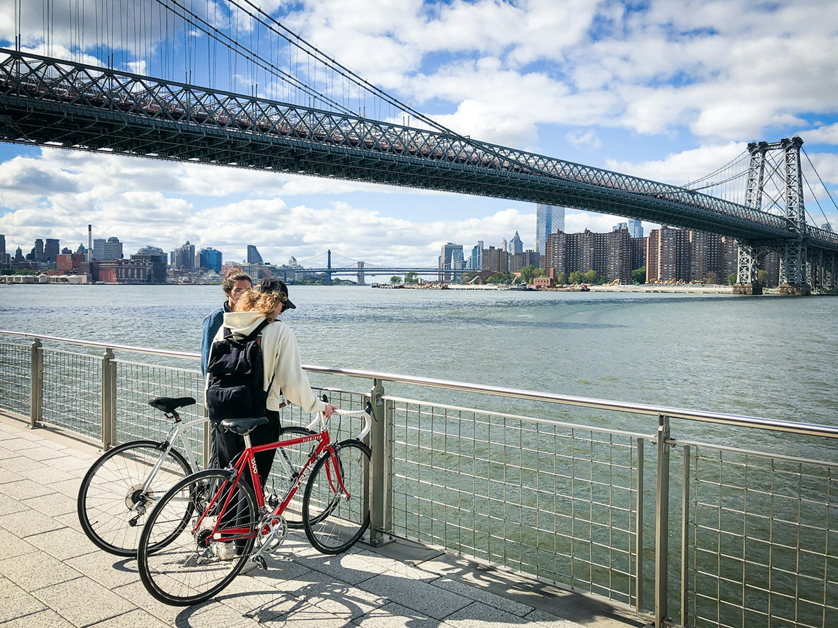 Two cyclists enjoying a view of the Manhattan skyline and Williamsburg Bridge