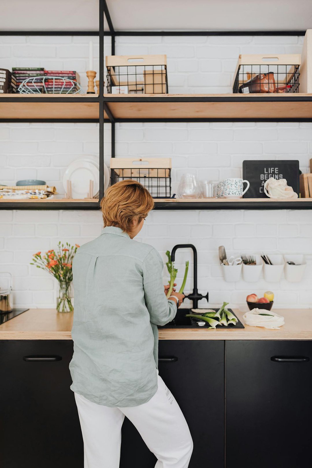 Woman at sink in modern kitchen washing vegetables