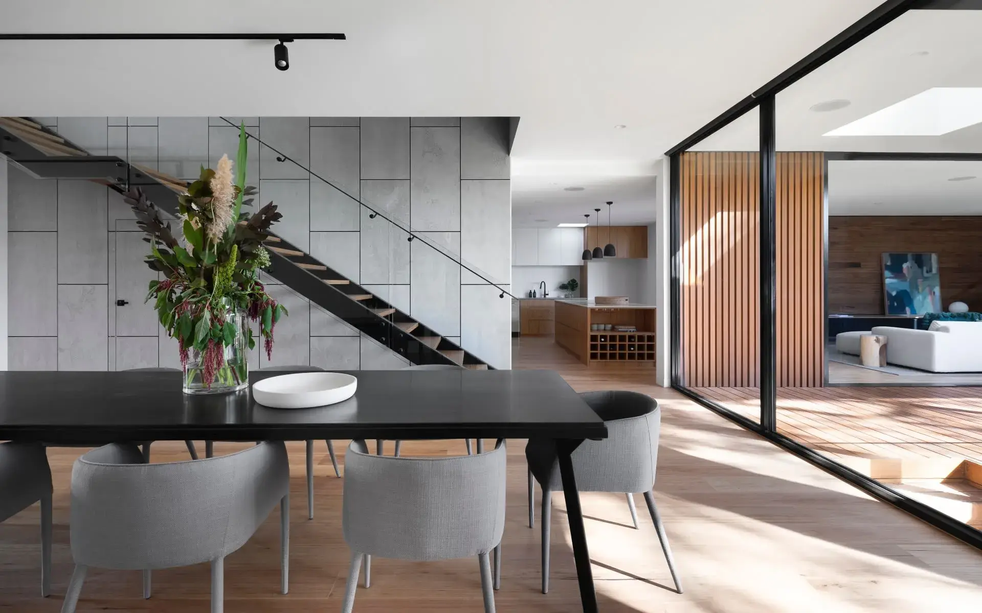 Modern minimalist dining area with staircase in the background.