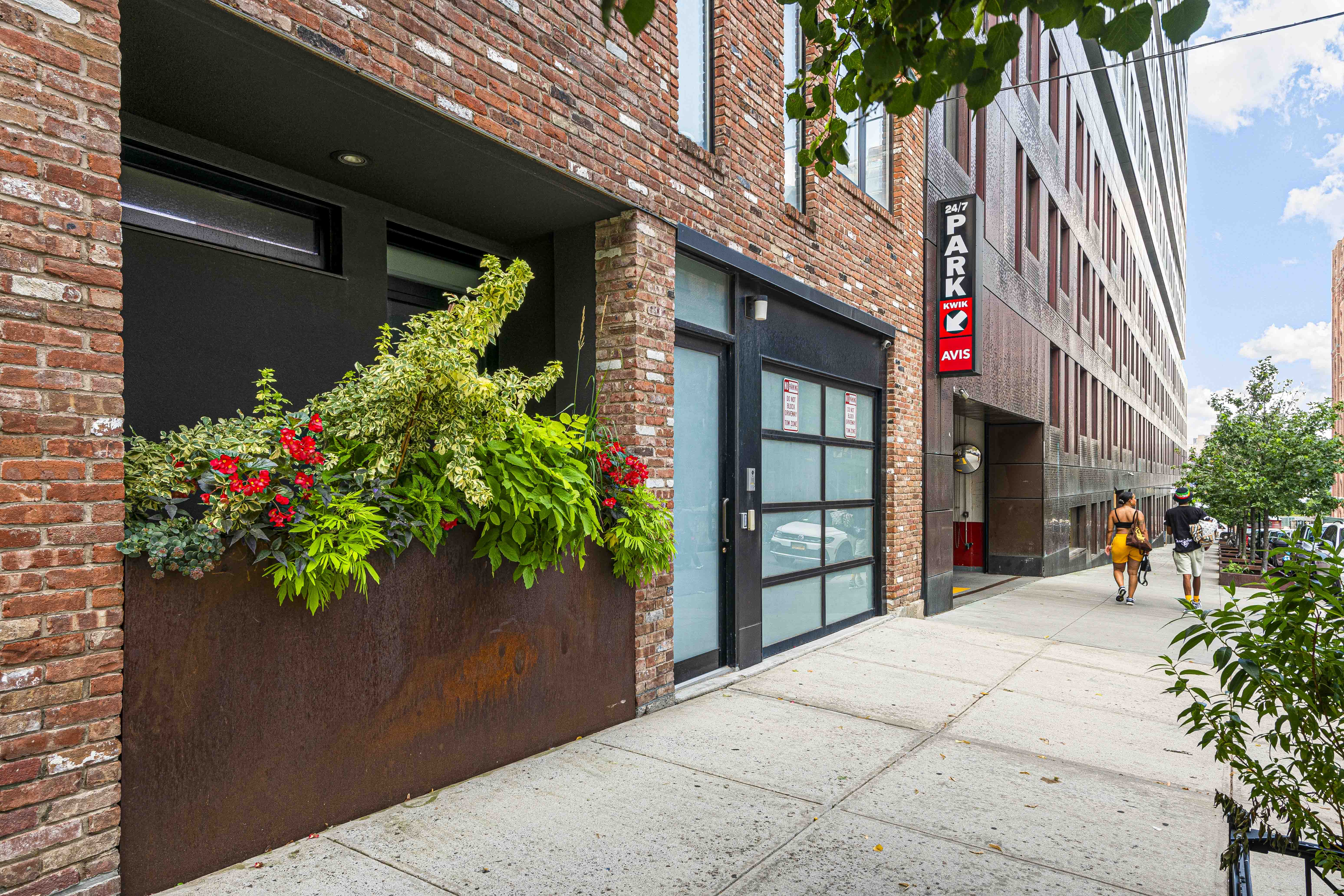 A stylish brick building entrance adorned with green plants, offering a welcoming urban aesthetic.