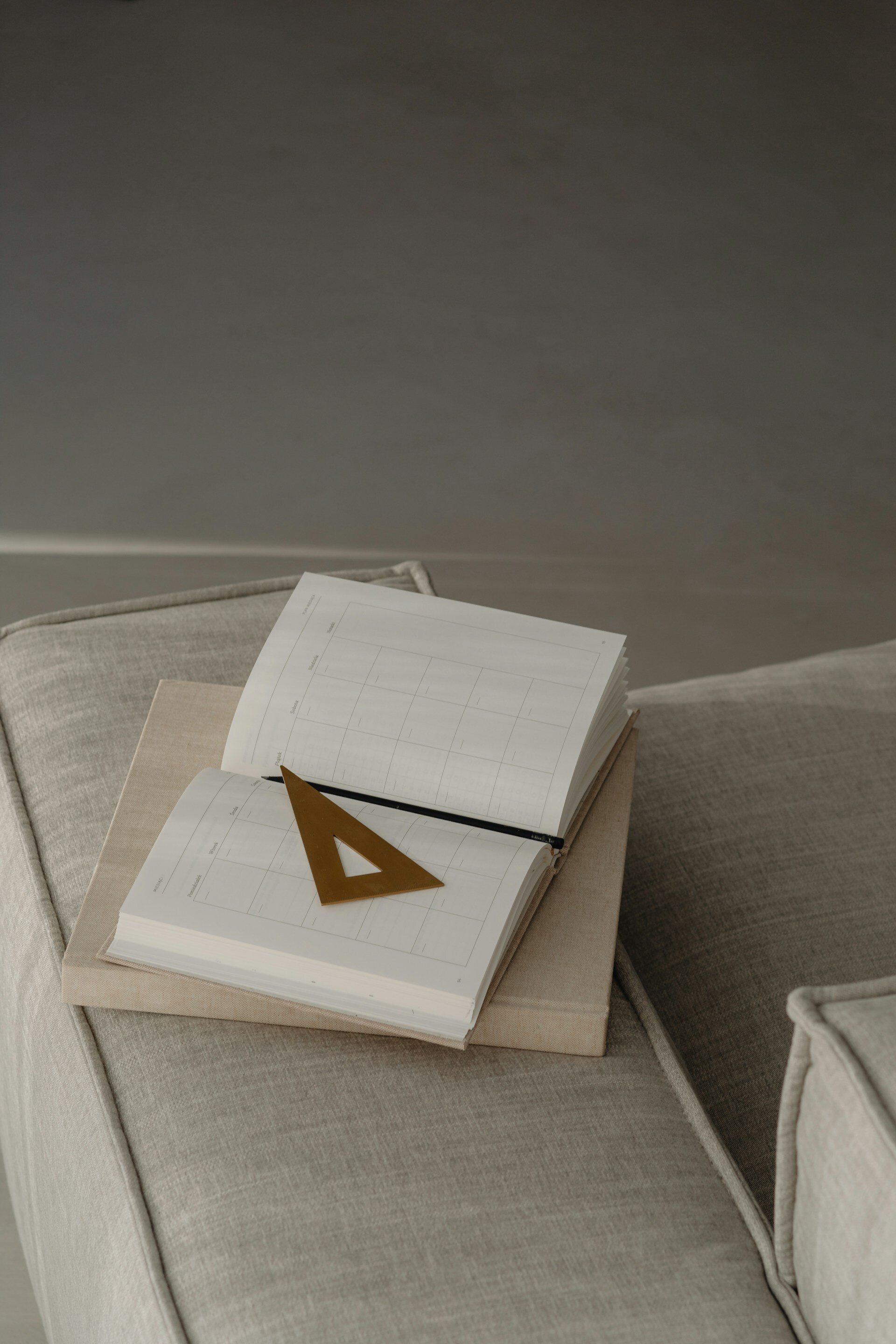 Open planner with a triangular ruler on a couch, representing meticulous planning for real estate investments.