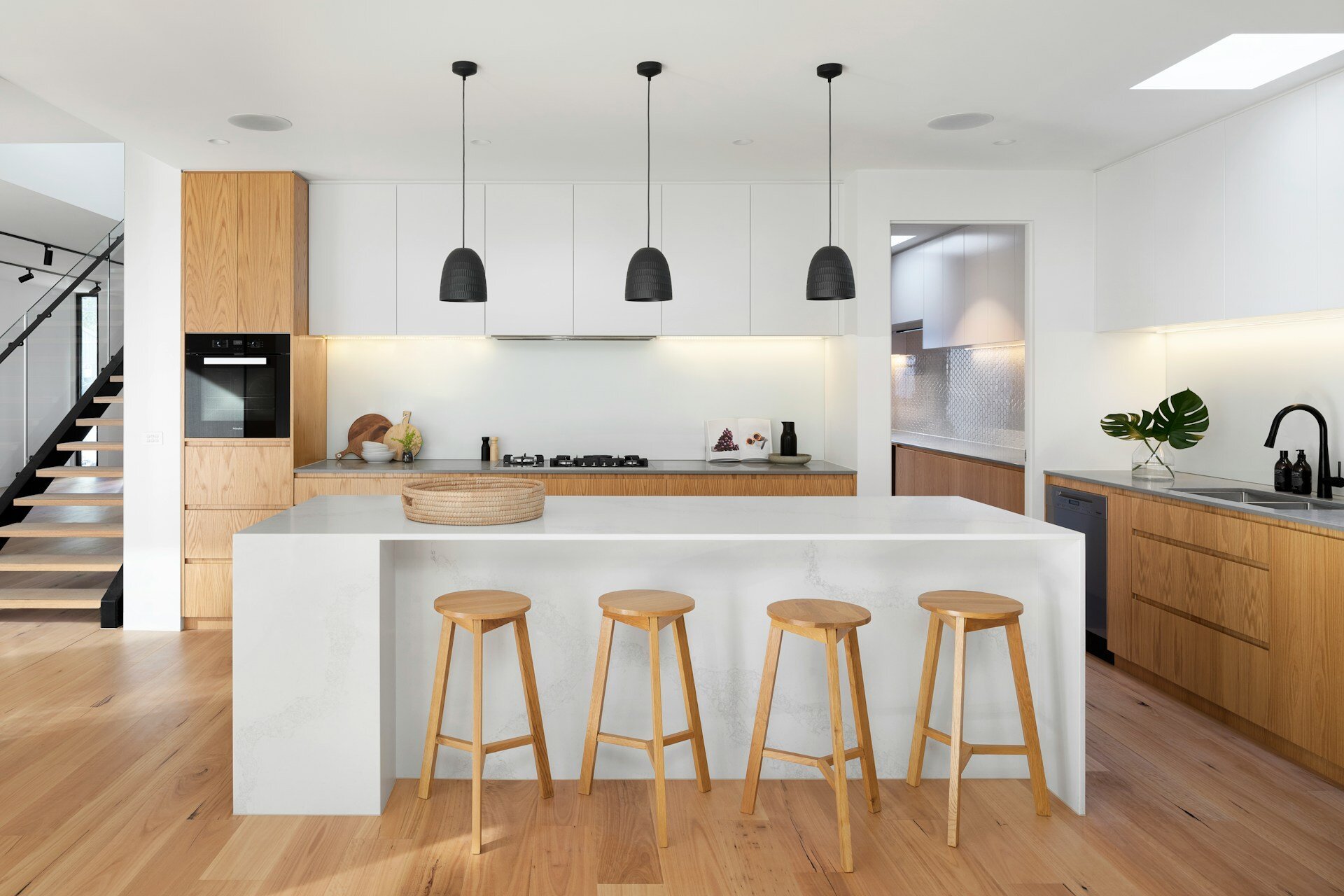 Stylish kitchen with white marble island, barstools, and pendant lighting.