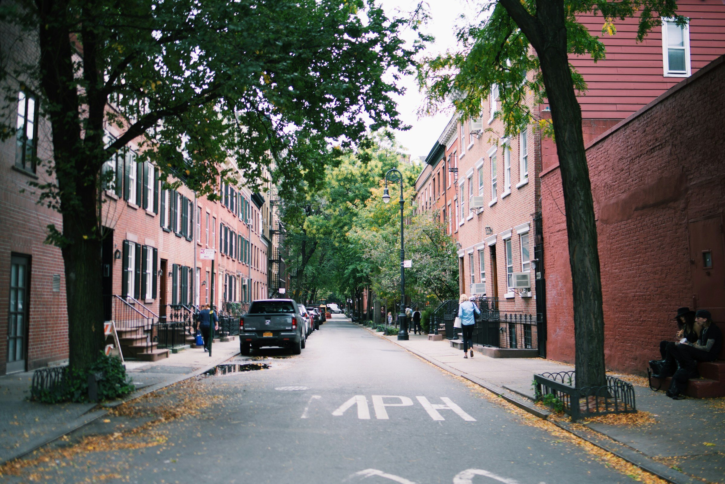 A charming tree-lined street in Greenwich Village, featuring historic brownstones and a quiet neighborhood ambiance.