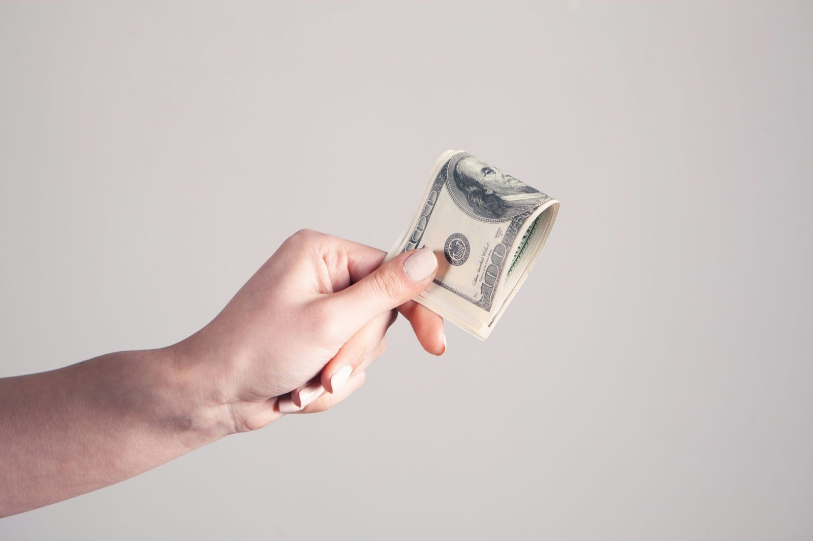 Person holding a stack of hundred dollar bills 