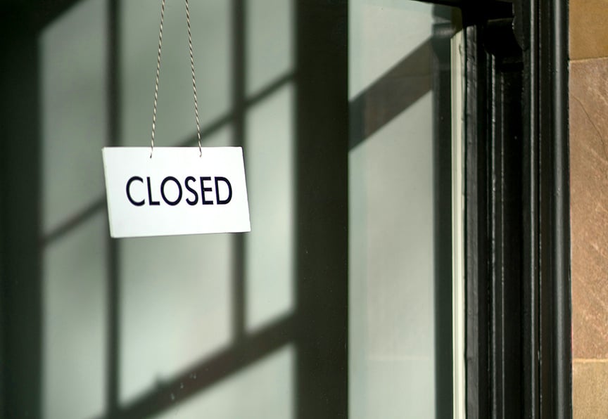 A 'Closed' sign on a glass door, symbolizing closing costs for real estate listings.