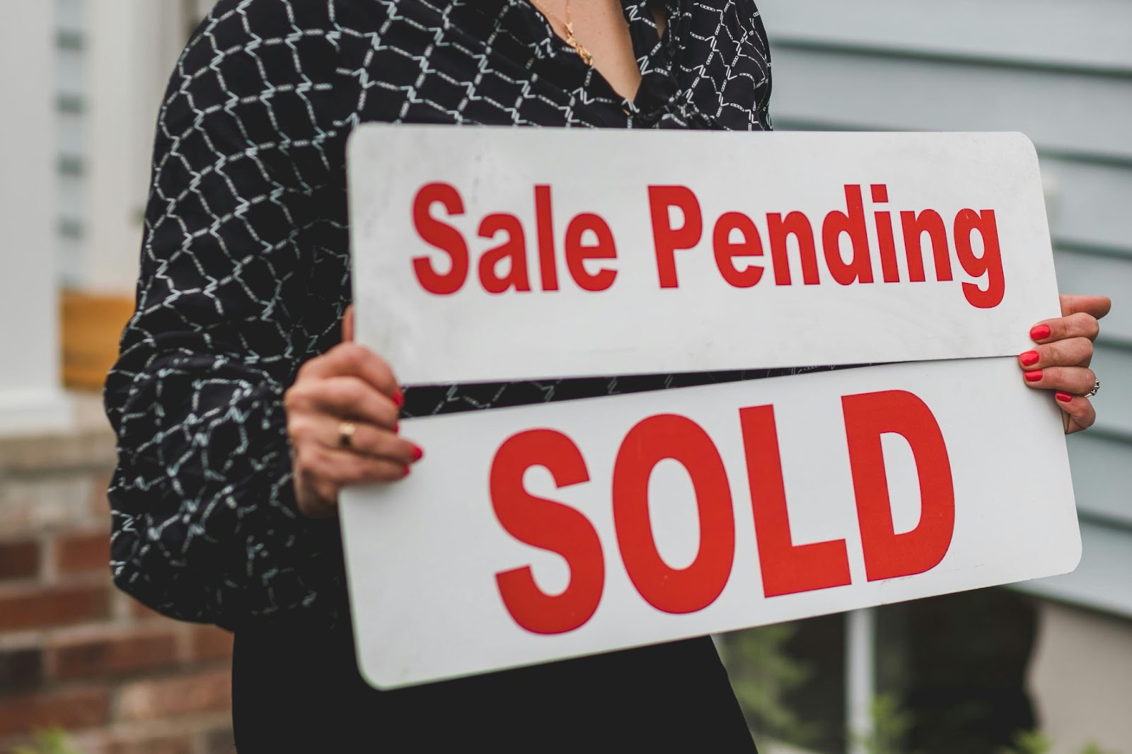 Person holding a sales pending and sold signs 