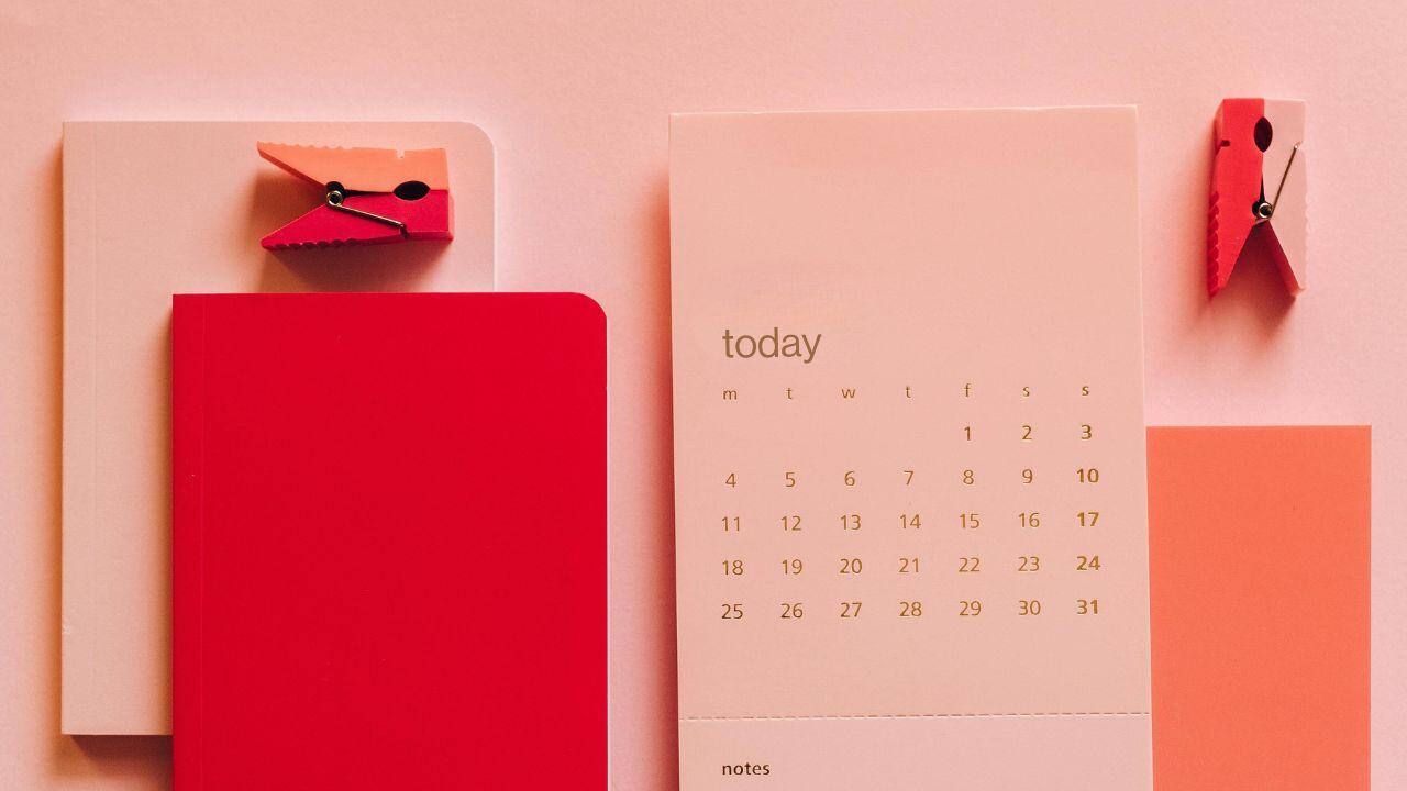 A calendar and red notebook on a desk, representing the importance of timing in the home selling process.