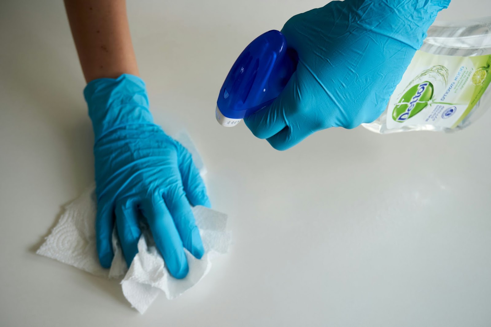 Person deep cleaning a surface with gloves and disinfectant 