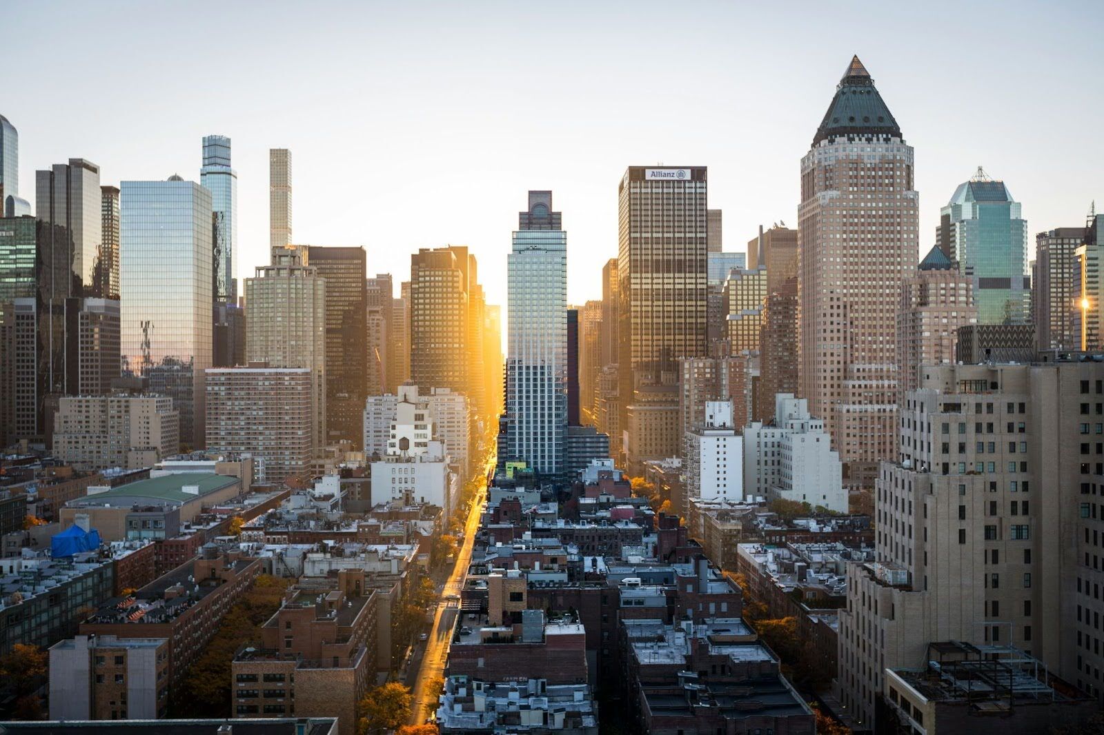 A view of a new construction building in NYC and the city skyline at sunset