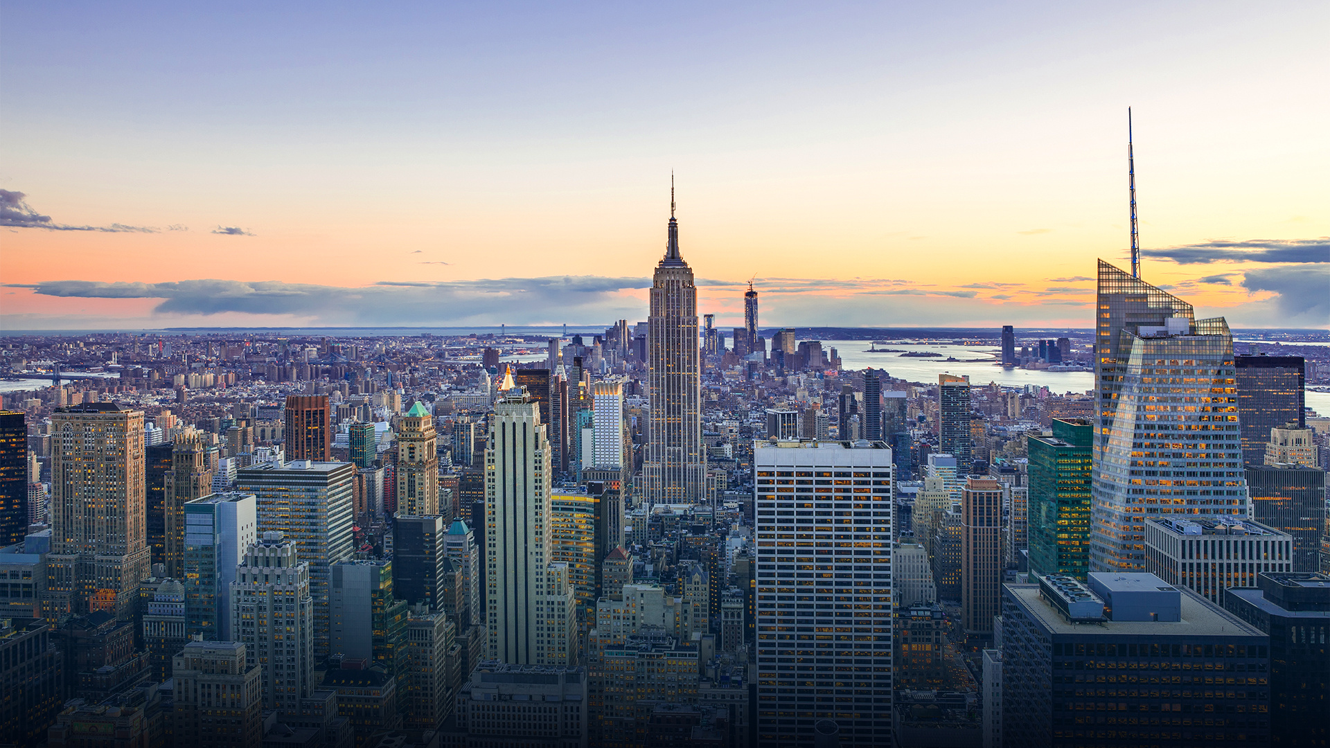 Iconic Empire State Building and Manhattan skyline at sunset, highlighting NYC real estate.