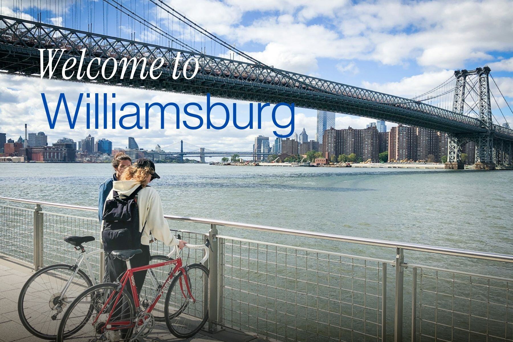 Two cyclists overlooking East River with Williamsburg Bridge skyline